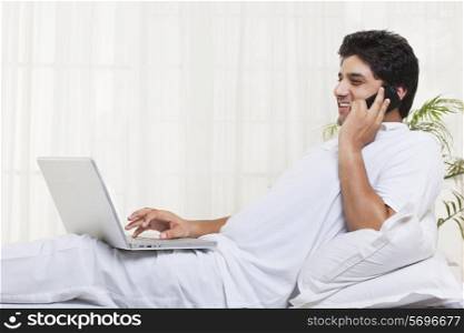 Smiling man having conversation while using laptop at home