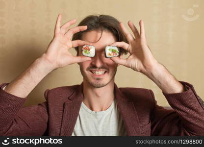 Smiling man hold sushi rolls instead of eyes. Traditional japanese seafood.