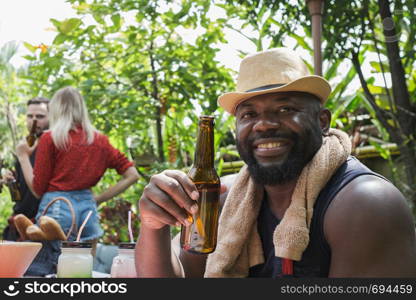 Smiling man holding beer for dinner camping in nature outdoor as summer lifestyle