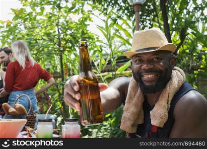 Smiling man holding beer for dinner camping in nature outdoor as summer lifestyle