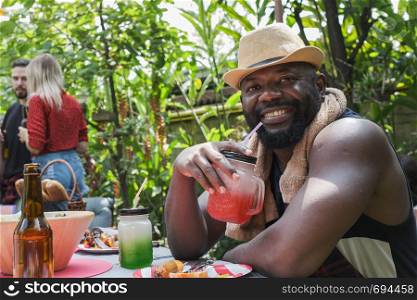 Smiling man holding glass of fruit juice for dinner camping in nature outdoor as summer lifestyle