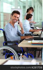 Smiling man in a wheelchair working in an office