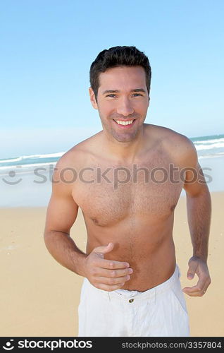 Smiling man jogging on a sandy beach