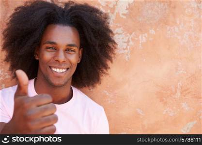 Smiling Man Leaning Against Wall Giving Thumbs Up