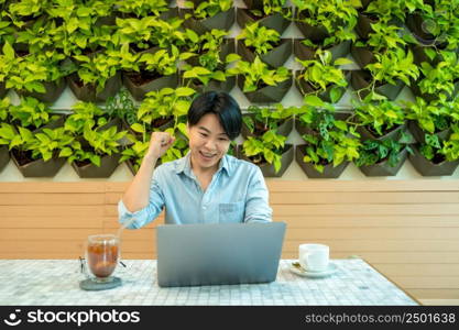 Smiling man looking at laptop screen,Checking finances,Sitting at table at home.