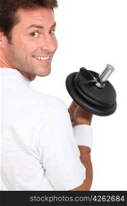 Smiling man looking over his shoulder holding dumbbell