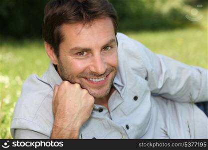 Smiling man lying in the grass