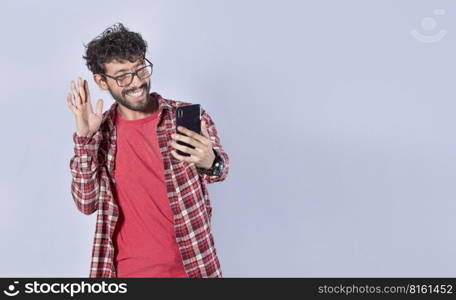 Smiling man making video call with his cellphone isolated, Positive teen guy making video call waving hands, Concept of smiling man saying hello by video call on cellphone