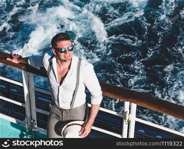 Smiling man on the empty deck of a cruise liner on the background of sea waves. Top view, close-up. Concept of leisure and travel. Smiling man on the empty deck of a liner