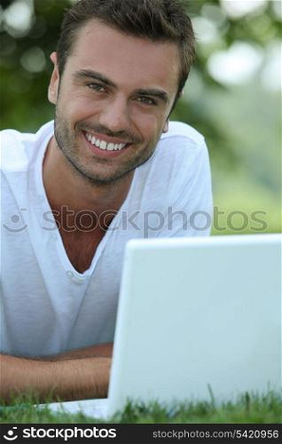 Smiling man outdoors with a laptop