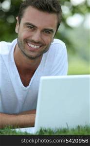 Smiling man outdoors with a laptop