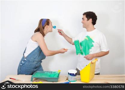 Smiling man painting his wife&rsquo;s nose with paint