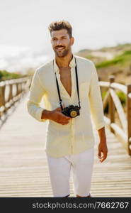 Smiling man photographing in a coastal area with an SLR camera. Smiling man photographing in a coastal area.