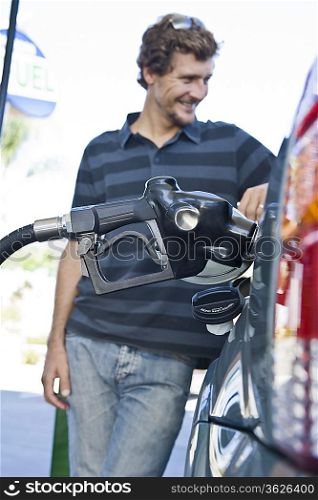 Smiling man refueling car at natural gas station