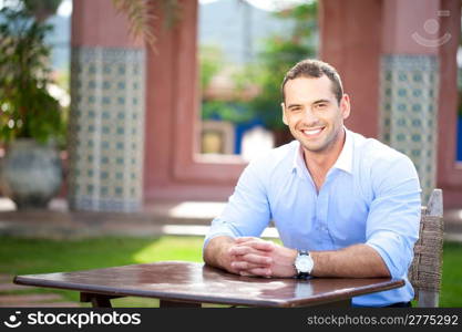 Smiling man seated at a table in a cafe