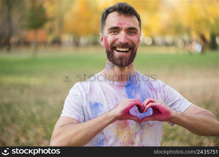 smiling man showing love sign with painted hands