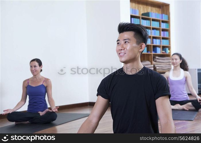 Smiling man sitting cross-legged in a yoga class