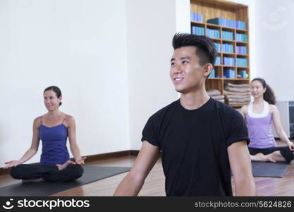 Smiling man sitting cross-legged in a yoga class