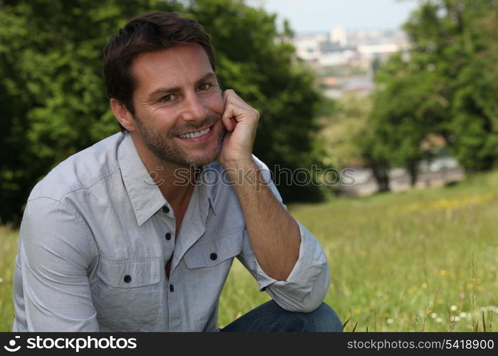 Smiling man sitting in a park