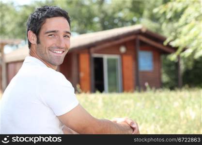 Smiling man sitting in front of a cabin