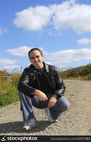 Smiling man sitting on a country road