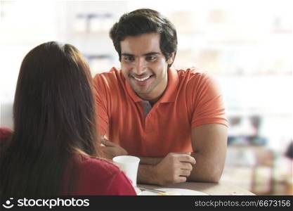 Smiling man sitting with girlfriend at restaurant