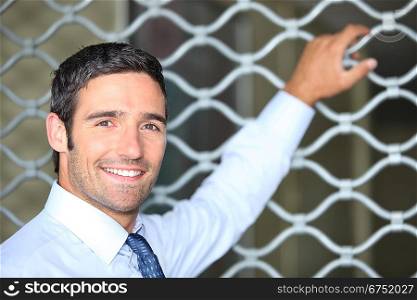 Smiling man standing in front of a shop grille