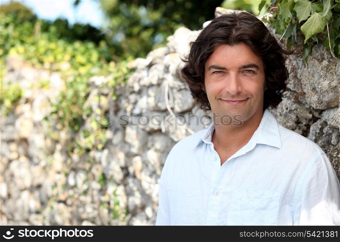 Smiling man standing in front of a stone wall