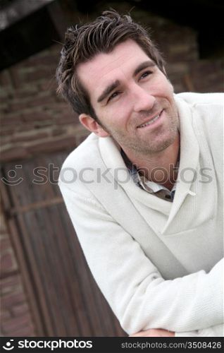 Smiling man standing in front of countryhouse