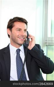 Smiling man using an office phone
