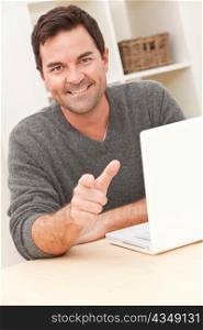 Smiling Man Using Laptop Computer At Home Pointing To Camera