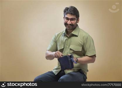 Smiling man wearing eyeglasses opening a small pouch or bag.