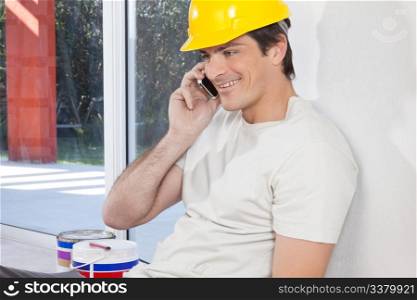 Smiling man with hard hat having conversation on mobile phone