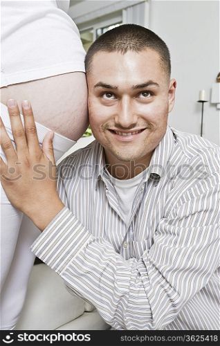 Smiling man with head at pregnant woman&acute;s abdomen
