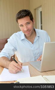 Smiling man working at home on laptop computer