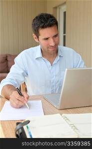 Smiling man working at home on laptop computer