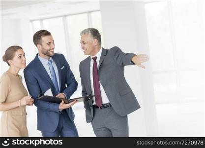 Smiling mature businessman gesturing to colleagues at new office