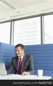 Smiling mature businessman using laptop at desk