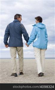 Smiling mature couple walking hand in hand on a beach