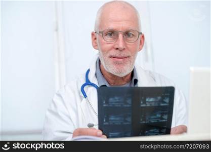 smiling mature Doctor looking at an x-ray in an office
