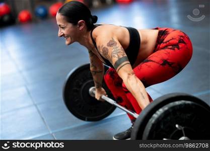 Smiling mature sportive woman weightlifting in a cross training gym. Smiling mature sportive woman weightlifting in a gym