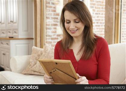 Smiling Mature Woman Looking At Picture Frame At Home