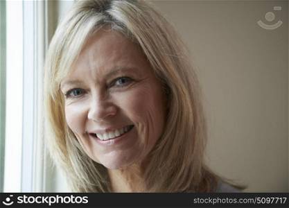 Smiling Mature Woman Standing Next To Window