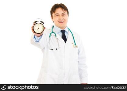 Smiling medical doctor holding alarm clock in hand isolated on white&#xA;