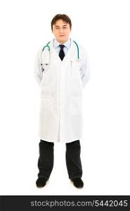 Smiling medical doctor holding hands behind his back isolated on white&#xA;