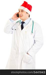 Smiling medical doctor in hat of Santa Claus talking on mobile phone isolated on white&#xA;