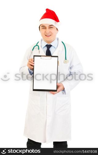Smiling medical doctor in Santa hat holding blank clipboard isolated on white&#xA;