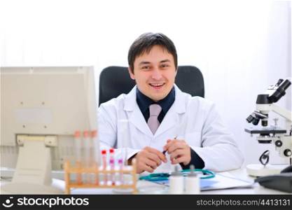 Smiling medical doctor sitting at table in office&#xA;