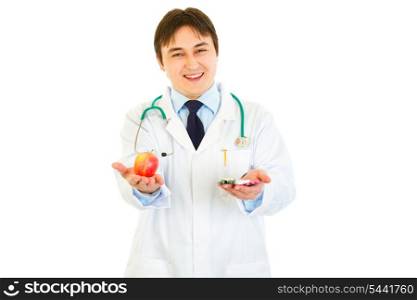 Smiling medical doctor with pills in one hand and apple in other isolated on white&#xA;