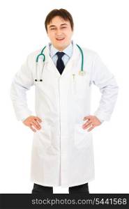 Smiling medical doctor with stethoscope holding hands on hips isolated on white&#xA;